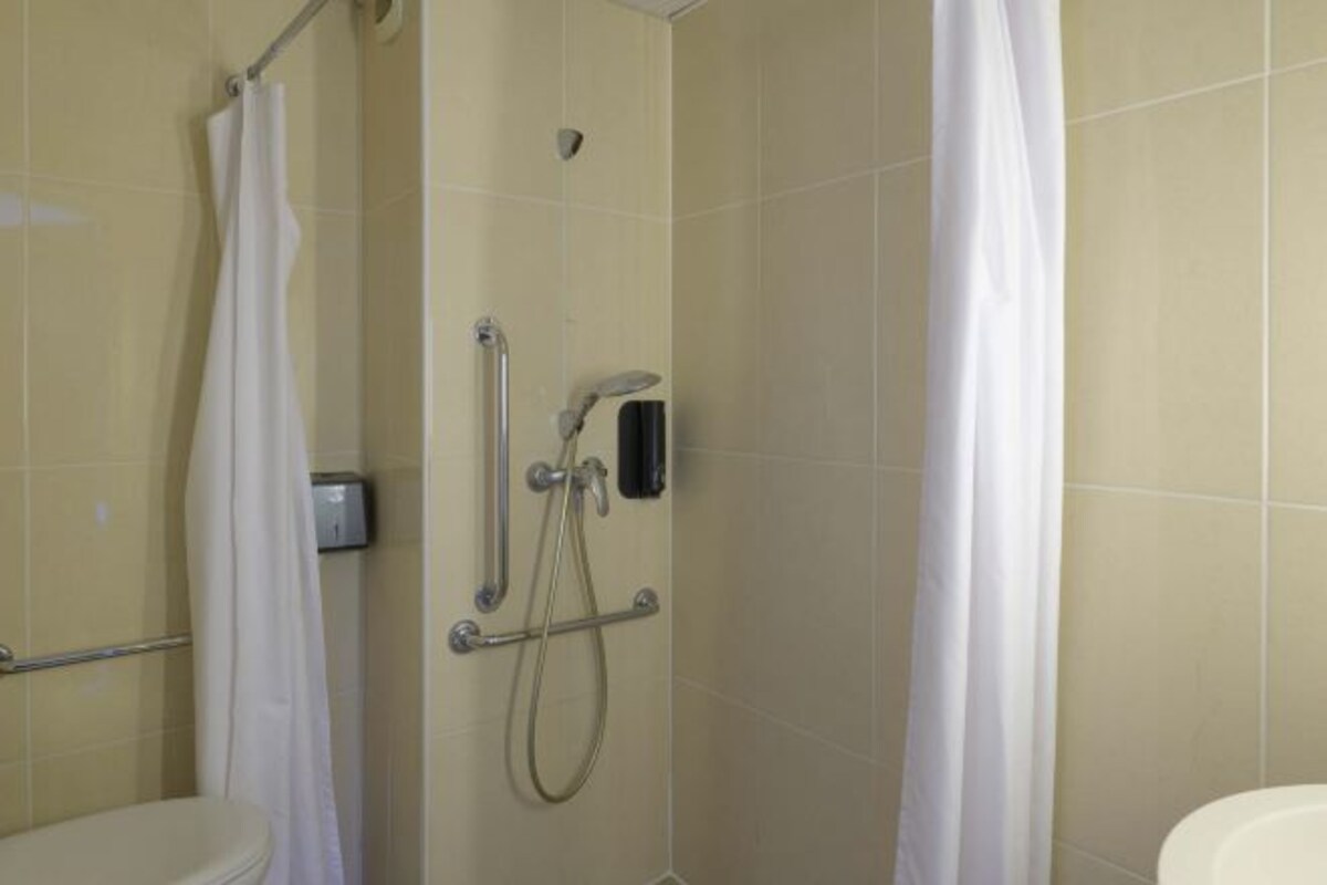 A bathroom with a shower, toilet, and a hand dryer.