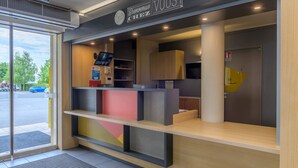 Een moderne receptie met een 'Bienvenue Chez Vous' bord, een digitaal scherm en uitzicht op de parkeerplaats.