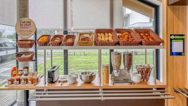 Un buffet de petit-déjeuner proposant un assortiment de pains et de viennoiseries, un grille-pain et diverses garnitures.