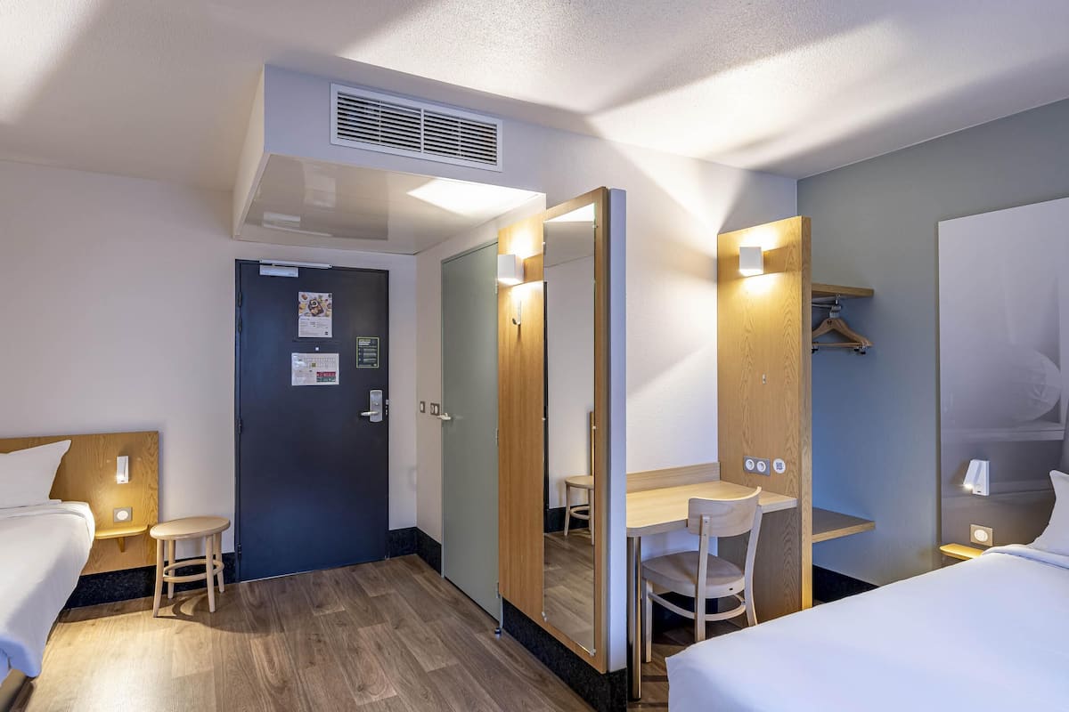 Ein Hotelzimmer mit Bett, Schreibtisch, Stuhl und Kleiderschrank.