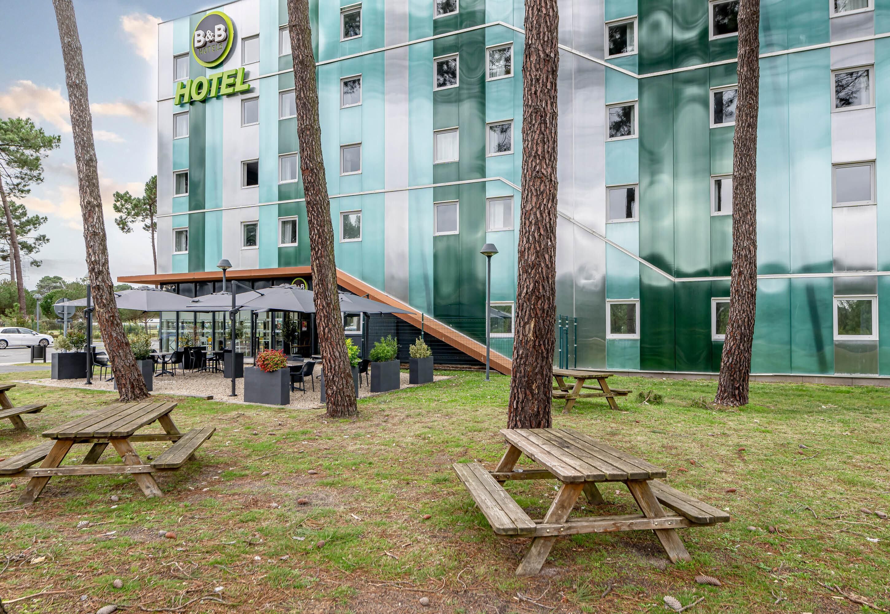 A hotel with a modern design, outdoor seating, and picnic tables.