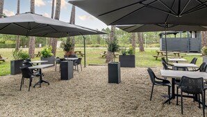 Un espace extérieur aménagé en terrasse, avec des tables, des chaises, des parasols et des jardinières.