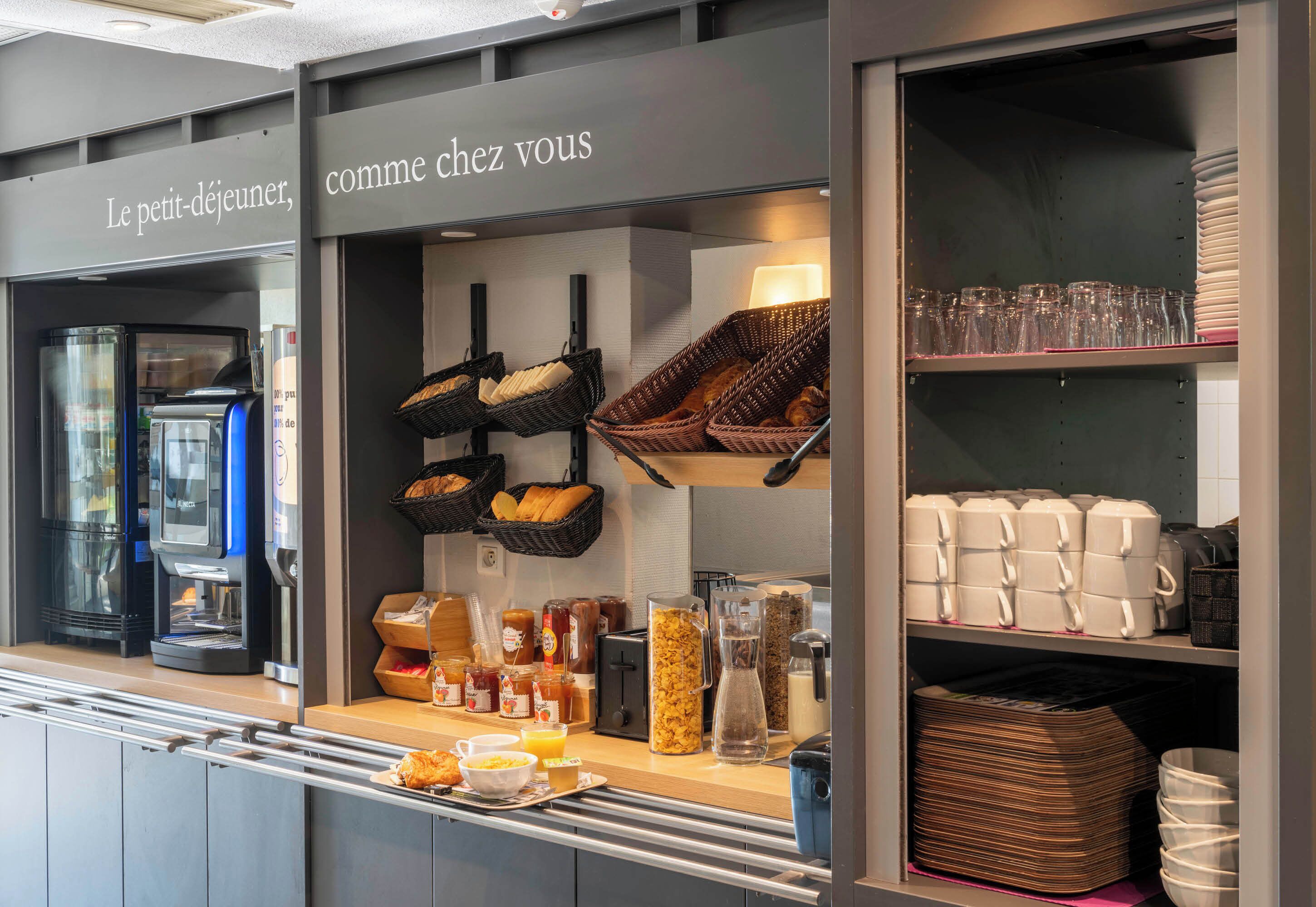 Een ontbijtbuffet met koffieautomaten, broodmanden en toevoegingen.