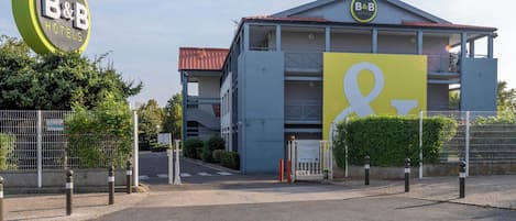 Un hotel tipo B&B con un letrero llamativo, una entrada con portón y un área de estacionamiento.