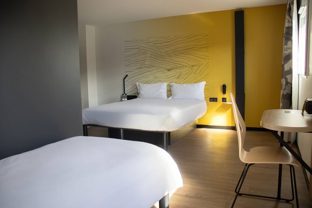 Habitació d'hotel amb llit, tauleta de nit, cadira i paret amb un disseny únic.