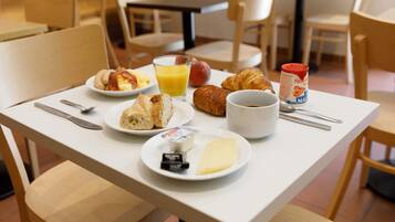 Un desayuno con platos de comida, un vaso de jugo de naranja y una taza de café sobre una mesa.