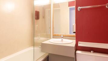 A bathroom with a white sink, a mirror, and a red wall.