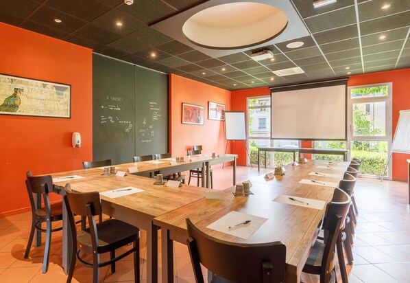 A conference room with a long table, chairs, a whiteboard, and a projector screen.