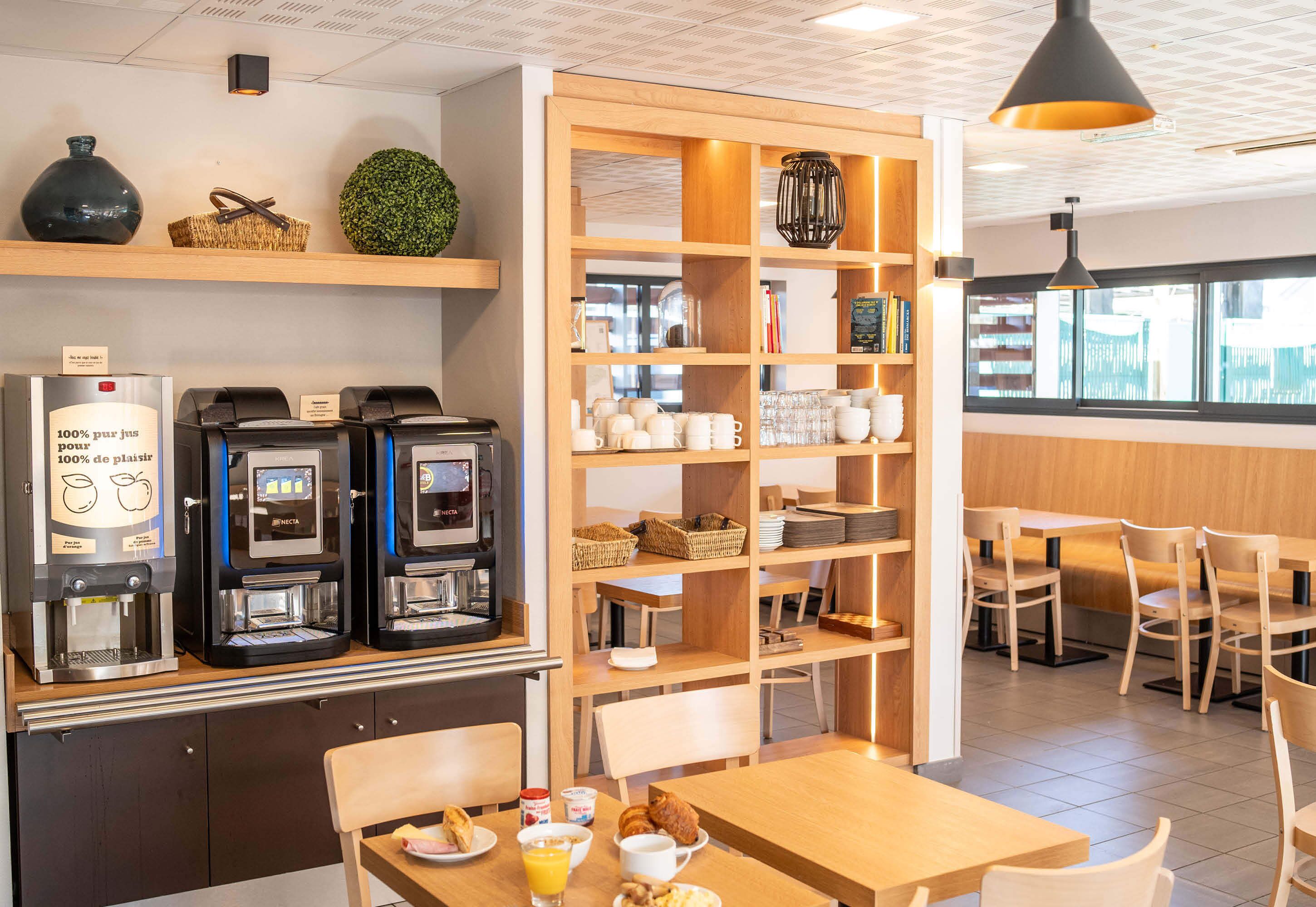 Una cafetería con máquinas de café, estantes con utensilios de cocina y zonas de estar.