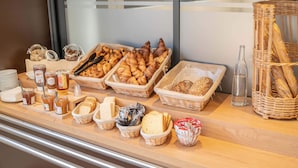 A breakfast buffet with various pastries, bread, and condiments.