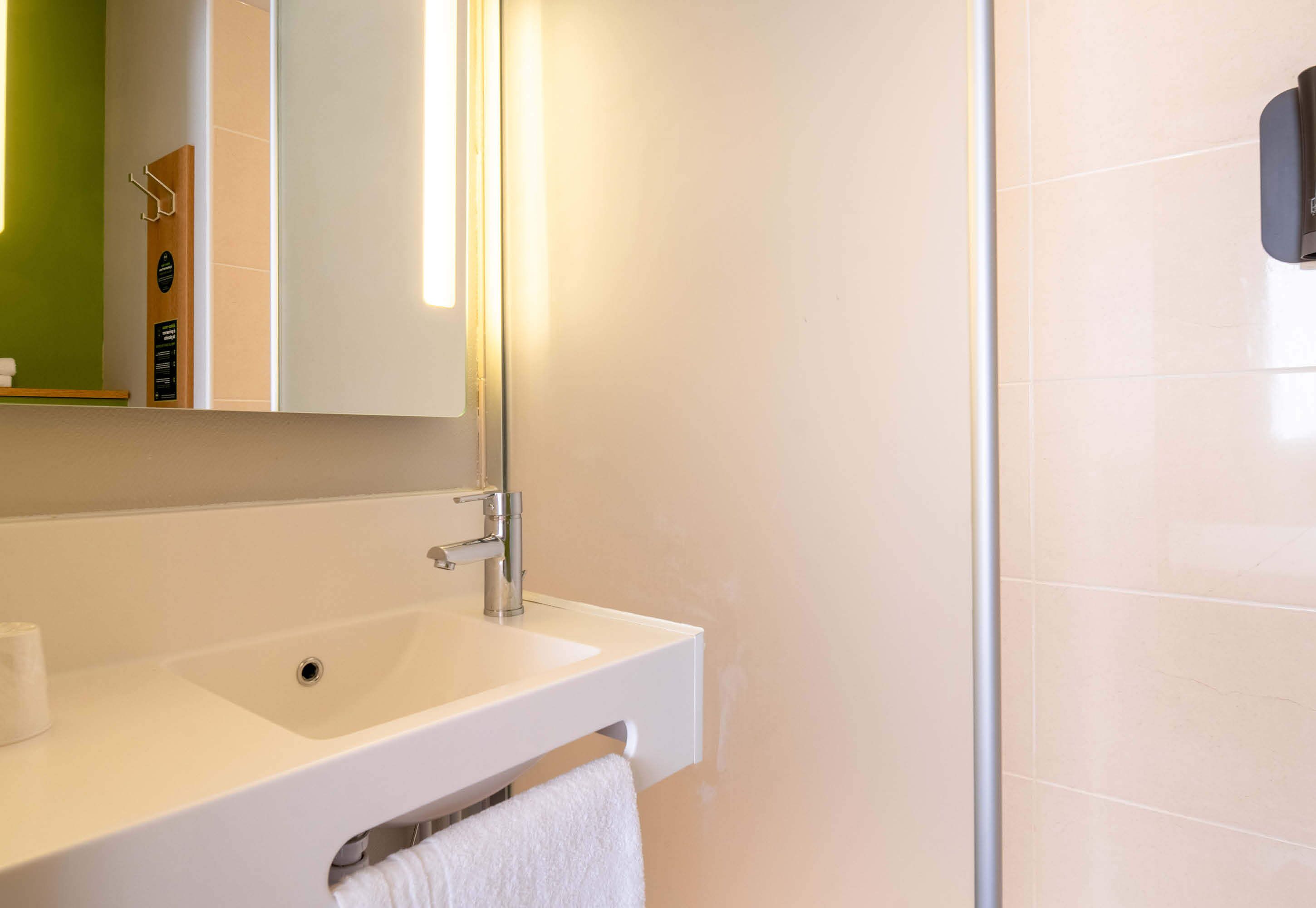 Une salle de bain avec un lavabo blanc, un miroir et un porte-serviettes.