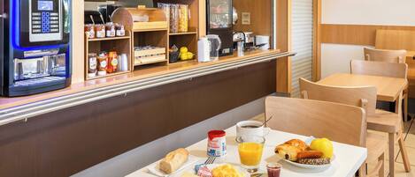 Una preparación para el desayuno con una cafetera, alimentos para el desayuno y una zona de estar.