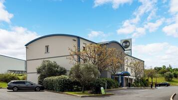 Ein Bed and Breakfast Hotel mit einer gebogenen Fassade, einem Schild und einem Parkplatz mit Autos.
