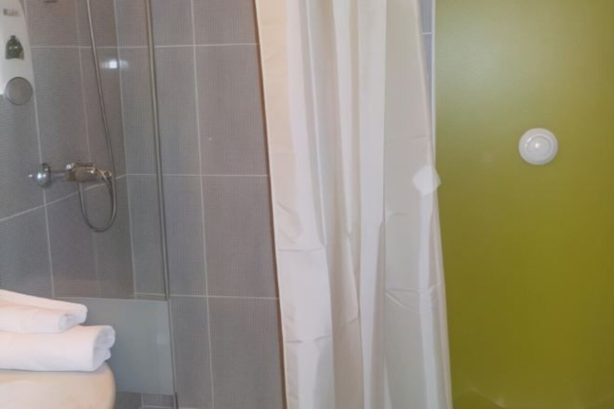 Un baño con ducha, inodoro y toallero.