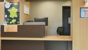 A reception desk with a map and welcome sign, a computer, and a chair. - B&B HOTEL Le Mans Nord 1 (Saint-Saturnin)