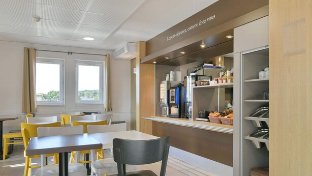 A modern cafe with a counter, seating area, and a view of the outdoors. - B&B HOTEL Le Mans Nord 1 (Saint-Saturnin)