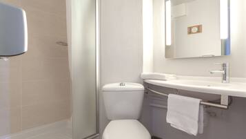 Un baño moderno con ducha acristalada, inodoro blanco y lavamanos con toallero.