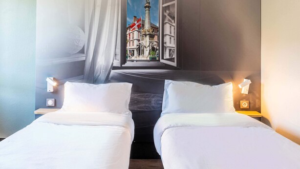 A hotel room with two beds, a window with a view of a building, and bedside lamps. - B&B HOTEL Chambéry La Cassine (Chambery)