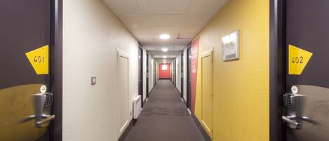A hotel corridor with doors numbered 401 and 402, featuring a carpeted floor and a red door at the end.