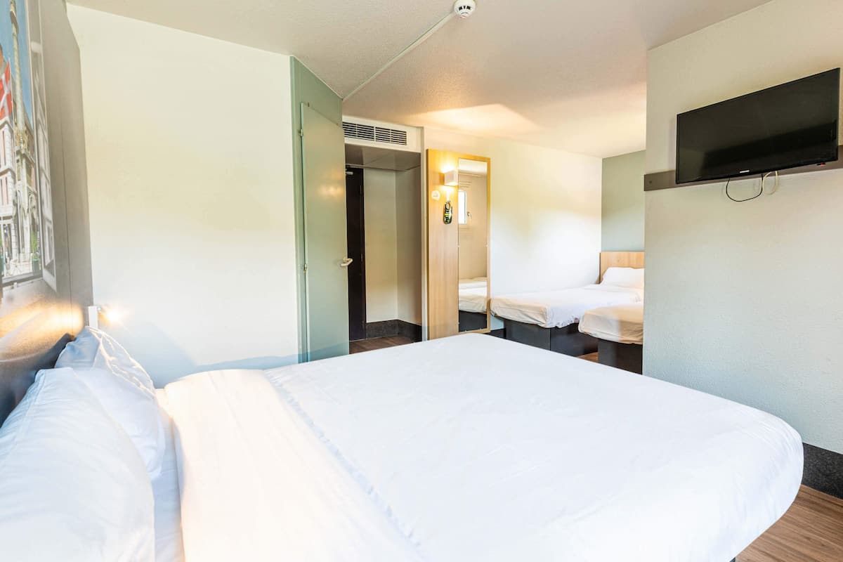 Une chambre d’hôtel avec un grand lit, un téléviseur fixé au mur et une porte donnant sur une salle de bain.