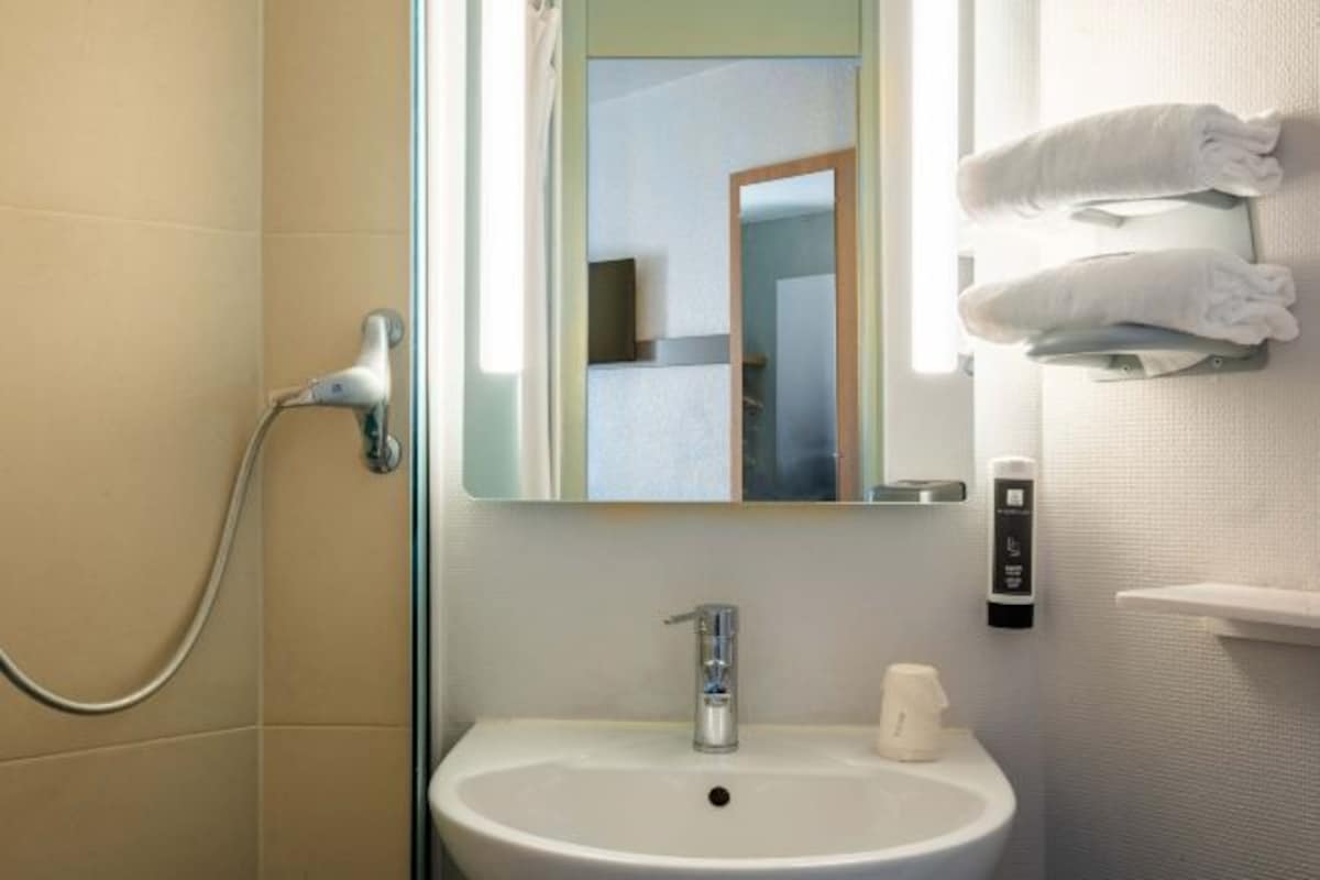 A bathroom with a white sink, a mirror, a towel rack, and a shower.