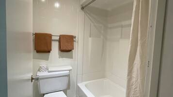 A modern bathroom with a toilet, bathtub, and shower curtain.