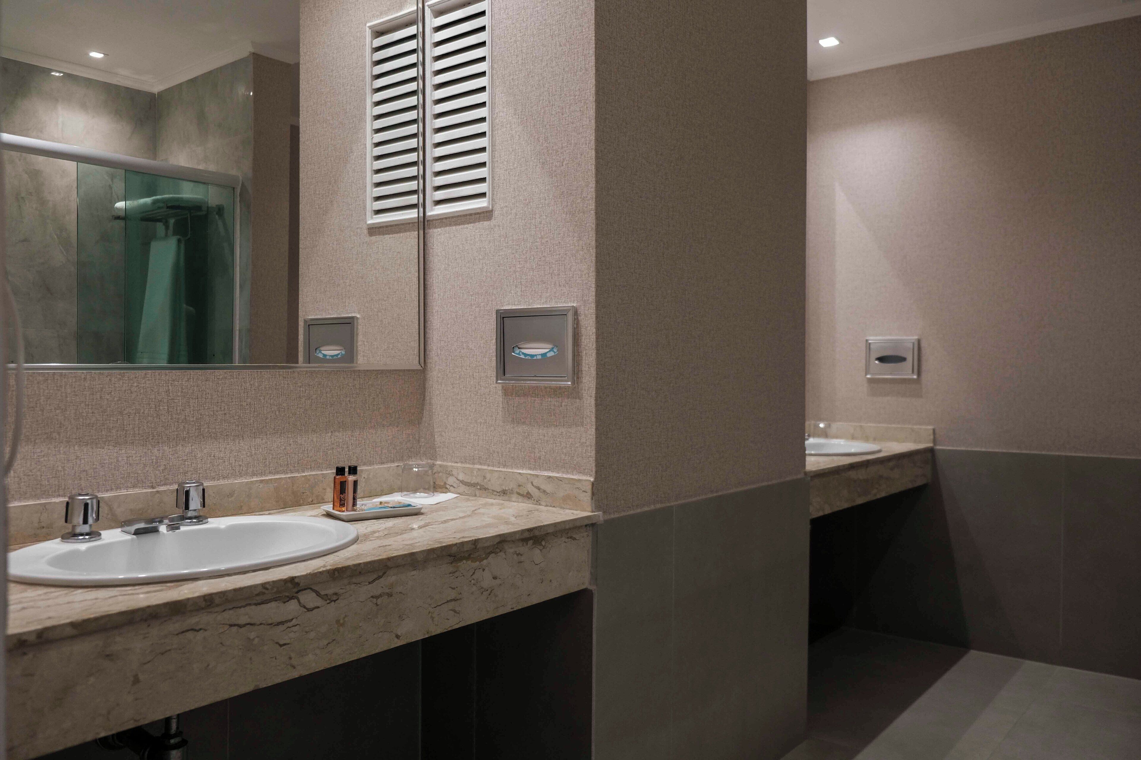 Un baño moderno con dos lavamanos, cabina de ducha de vidrio y espejo.