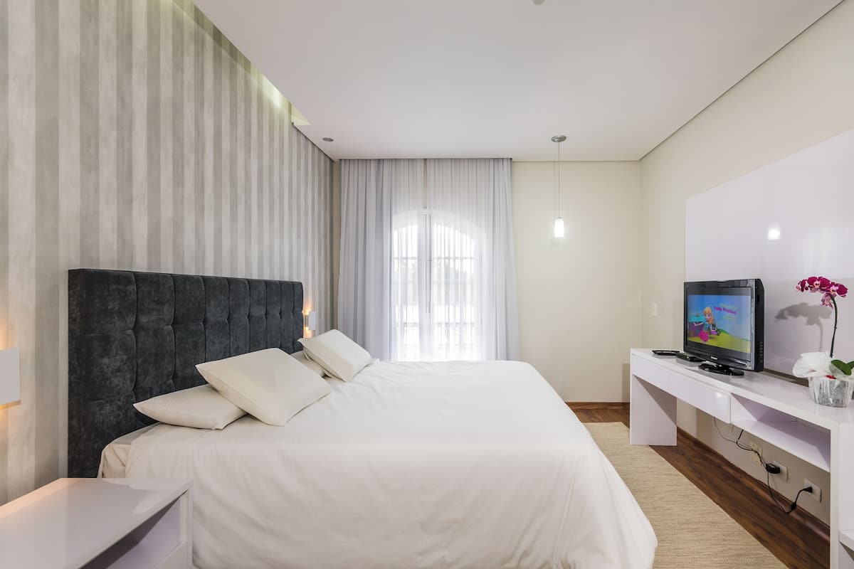 Una habitación de hotel moderna con una cama grande, un televisor de pantalla plana y un escritorio con una computadora.