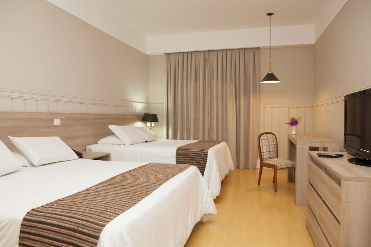 Habitación de hotel con dos camas, un televisor, un escritorio y una silla.