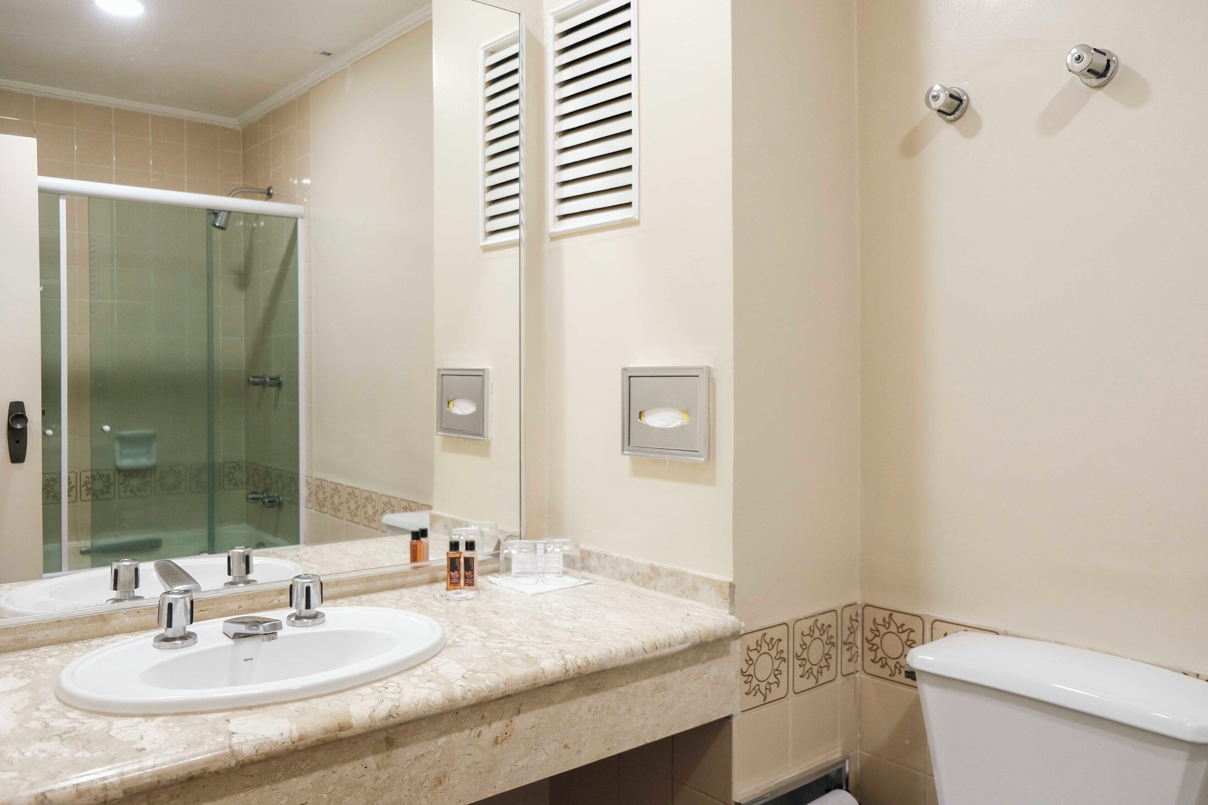 A bathroom with two sinks, a glass shower enclosure, and a toilet.