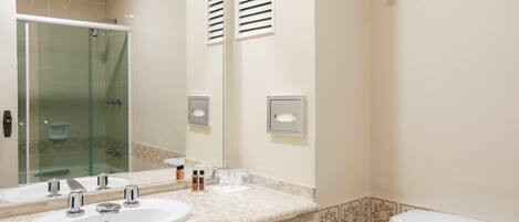 A bathroom with two sinks, a glass shower enclosure, and a toilet.