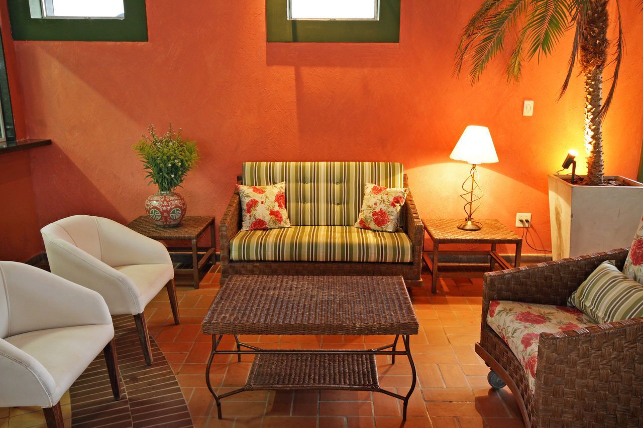 A cozy living room with a striped sofa, two white armchairs, a wicker coffee table, and a small side table with a lamp.