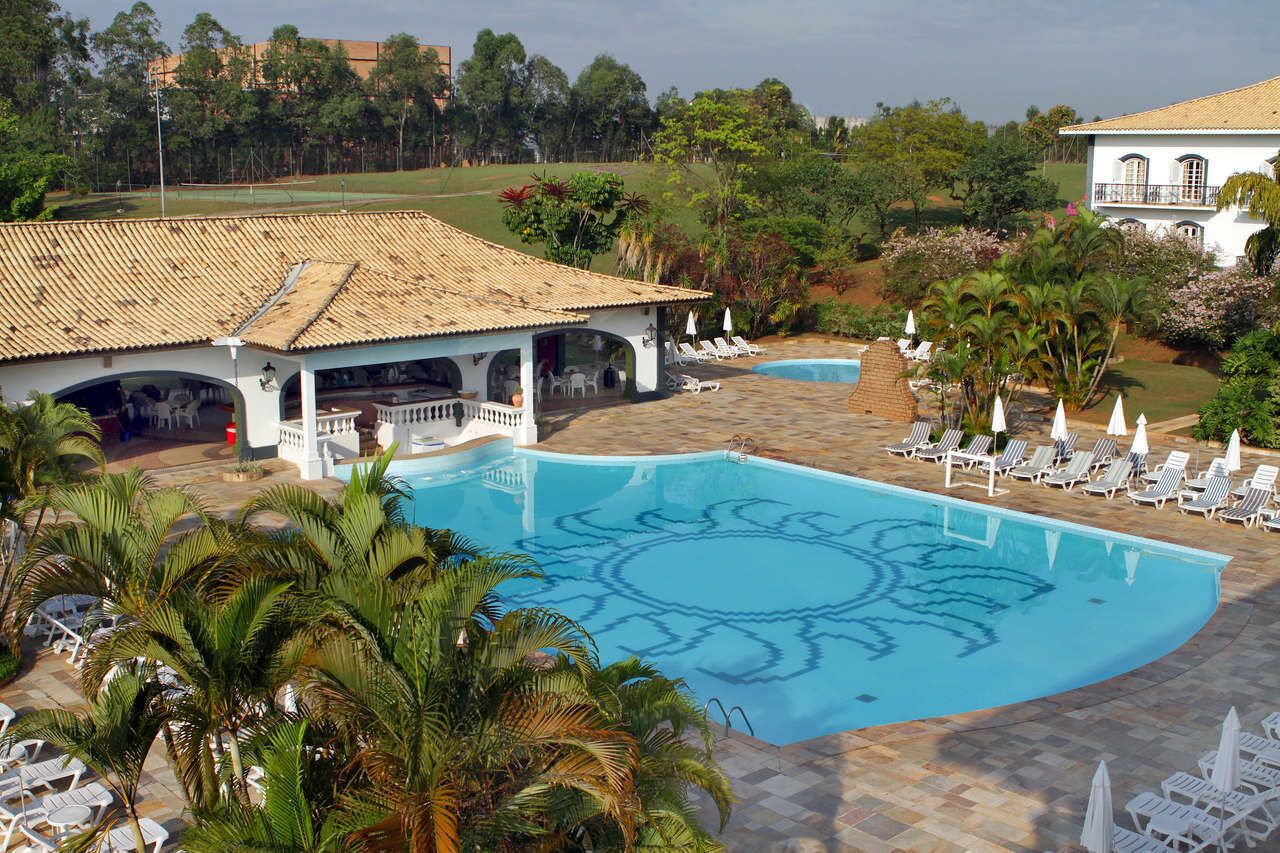 Una piscina con diseño geométrico, rodeada de sillones de descanso y palmeras.