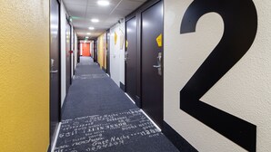 A hallway with doors numbered 2, 3, and 4, and a carpet with writing. - B&B HOTEL Saint-Michel-sur-Orge (Saint-Michel-sur-Orge)