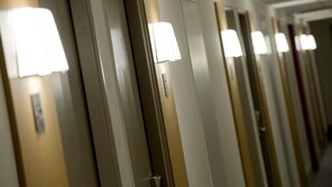 Een hotelgang met deuren, elk met een lamp erboven.