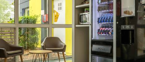 A modern interior with a vending machine, a microwave, and seating area.