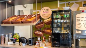 Mostrador de panadería con cestas de pan, frascos de conservas y una máquina de café.