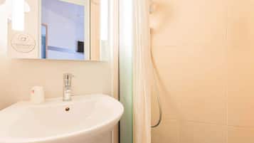 Un baño con lavamanos blanco, un espejo y cortina de ducha.