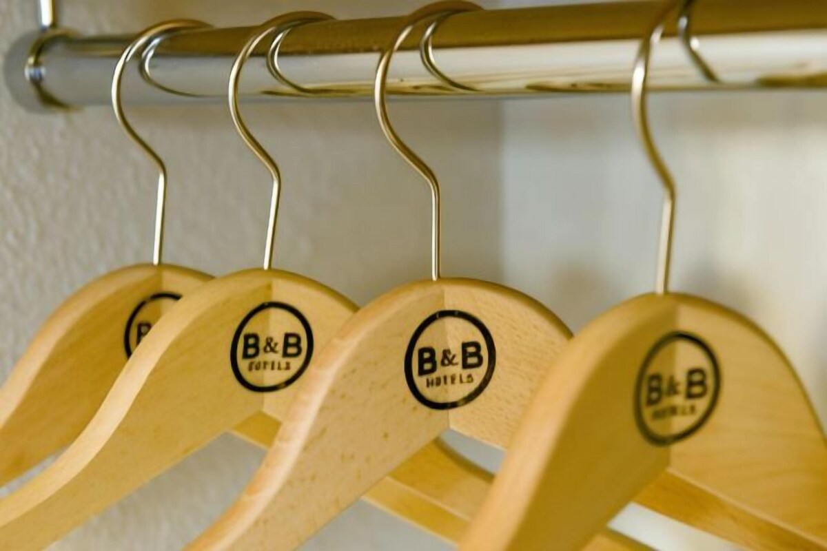 Een rek houten kledinghangers met 'B&B' logo's, wat duidt op een hotel of bed en ontbijt omgeving.