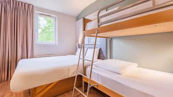 Une chambre avec un lit superposé, une échelle, une fenêtre avec des rideaux et un radiateur.