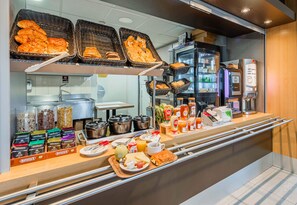 Un buffet de petit-déjeuner proposant une variété d’aliments, des paniers de pain, des condiments et une machine à café.