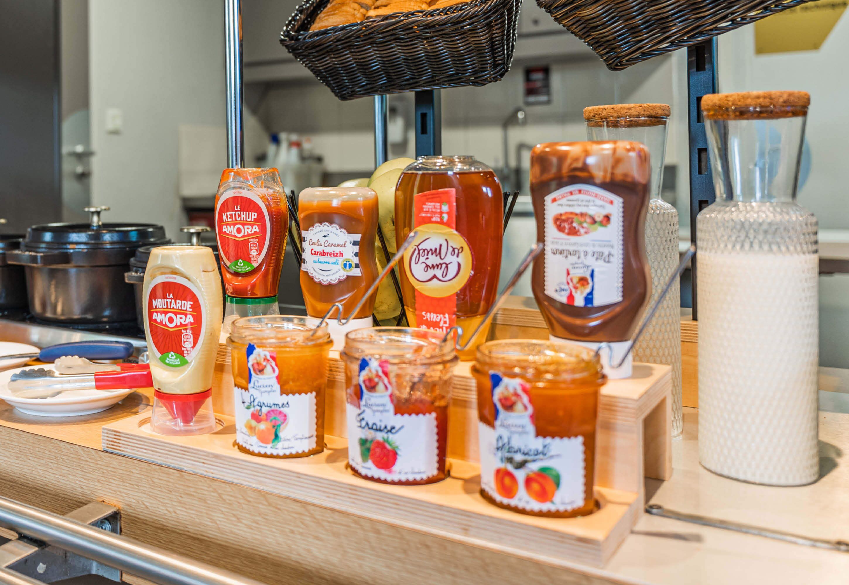 A variety of condiments and sauces displayed on a wooden counter in a kitchen setting.