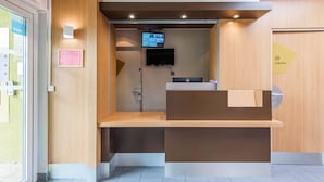 Een receptiebalie met een flatscreen televisie, een digitaal display en een bordje dat een lokaal privédomein aangeeft.