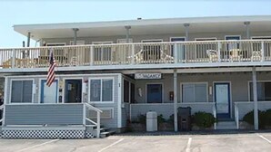 Un motel con una estructura de dos pisos, un porche cubierto y un estacionamiento.