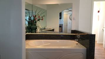 A modern bathroom with a freestanding bathtub, a large mirror, and a vase with flowers on the vanity.