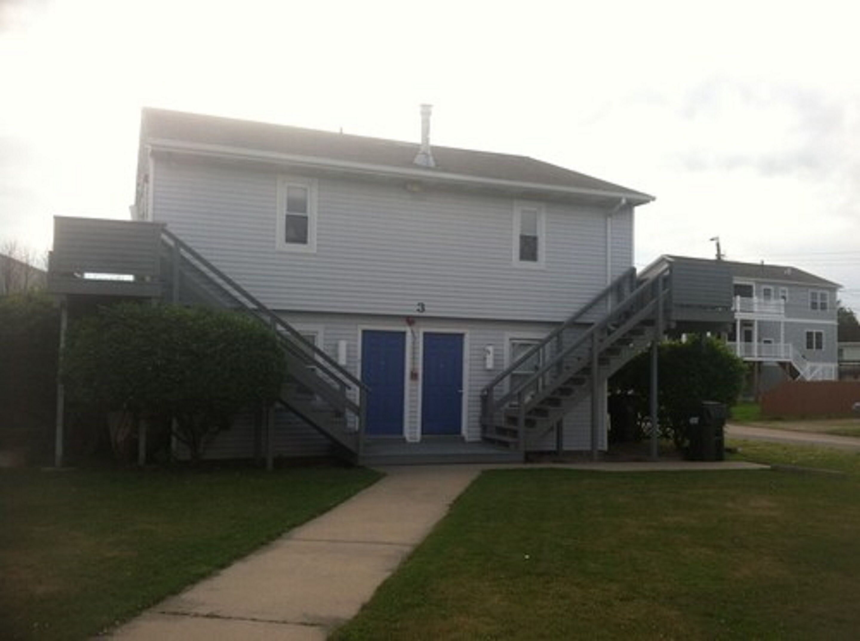 A two-story building with a blue door and a staircase leading to the entrance.
