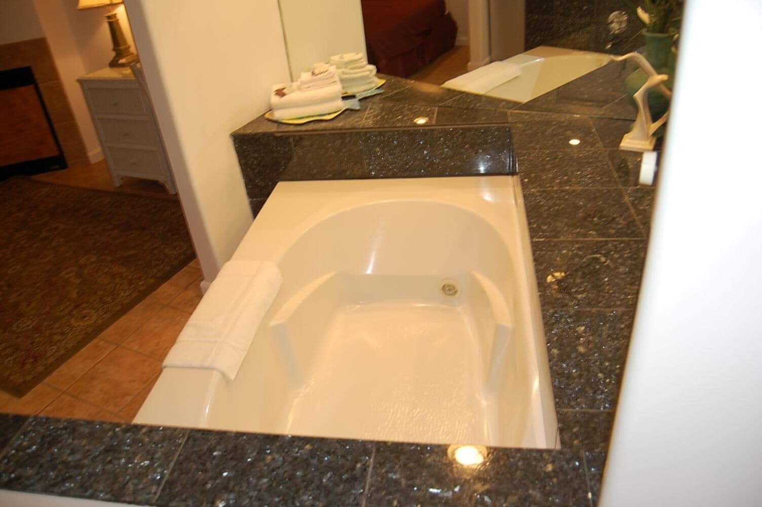 Un baño con una bañera grande, un lavabo y un espejo.