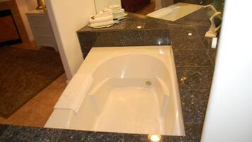 Un baño con una bañera grande, un lavabo y un espejo.