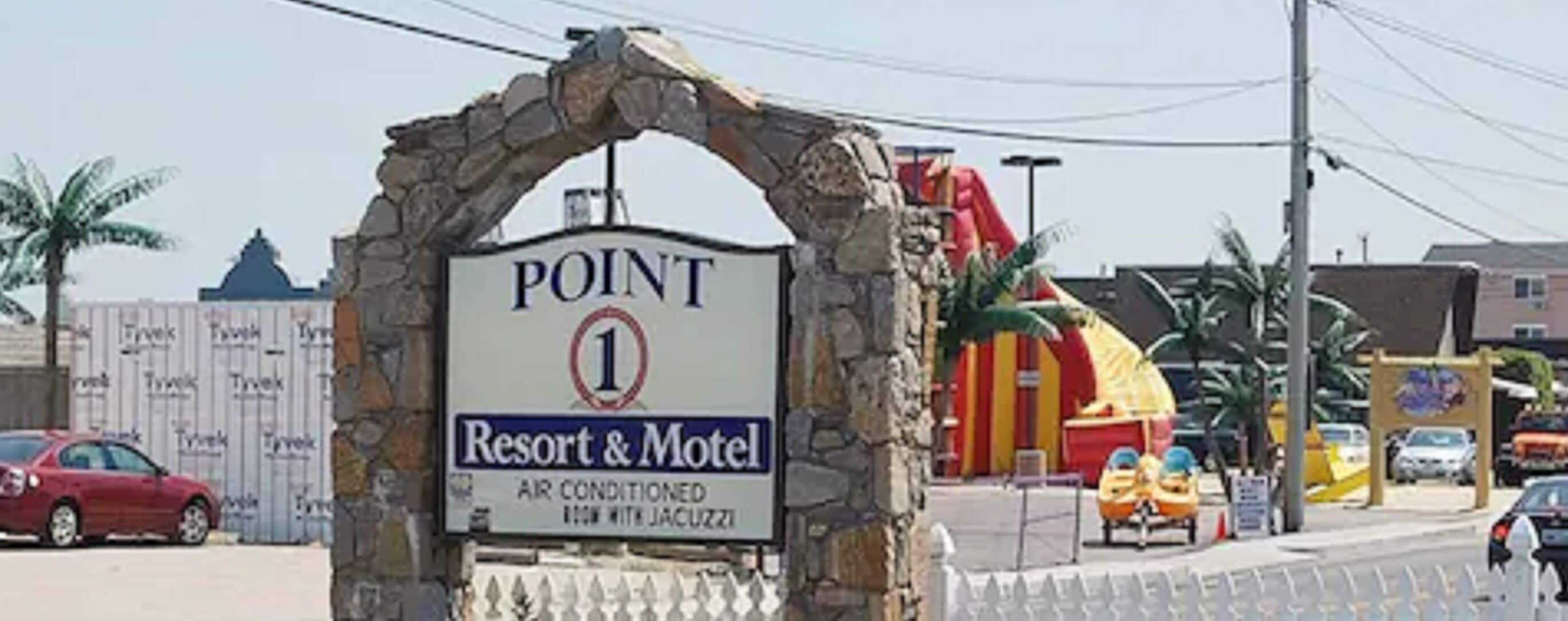 Een bord voor Point Resort & Motel met een bogenpoort, dat aangeeft dat dit de eerste locatie is.