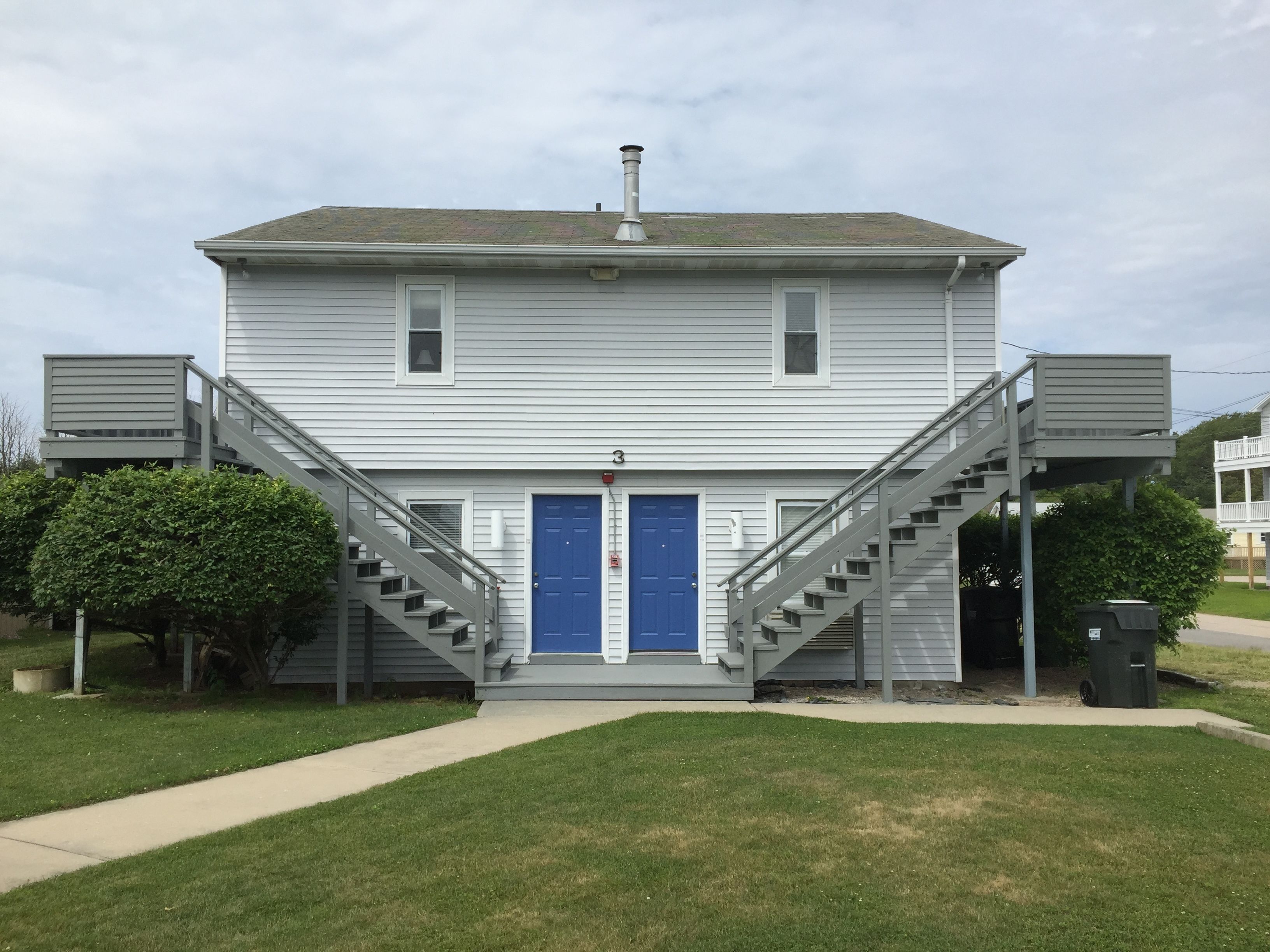 A two-story building with a blue door and two staircases on either side.